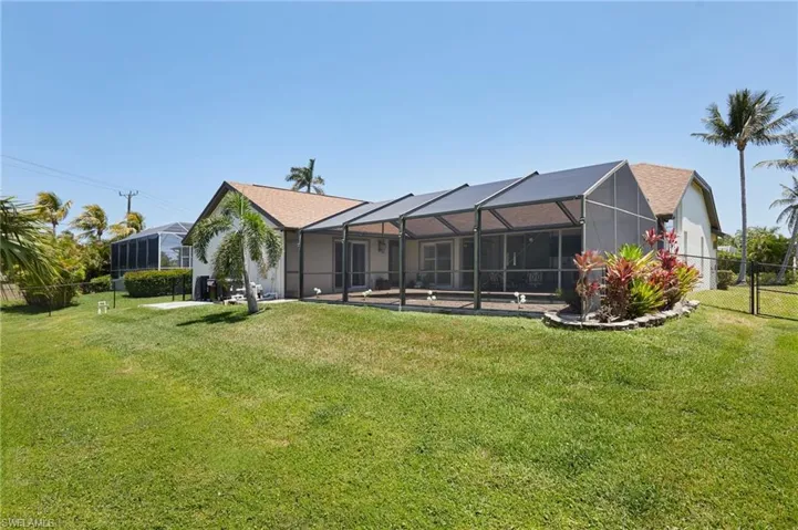 Back of property featuring a yard, a lanai, and fence
