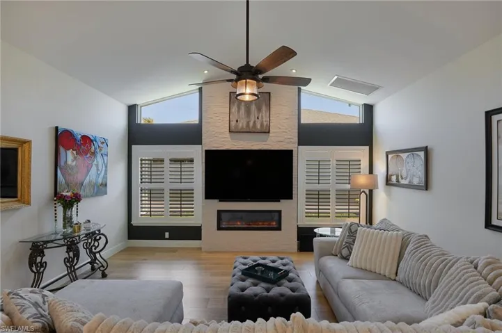 Living room with lofted ceiling, a ceiling fan, a healthy amount of sunlight, and wood like finished floors
