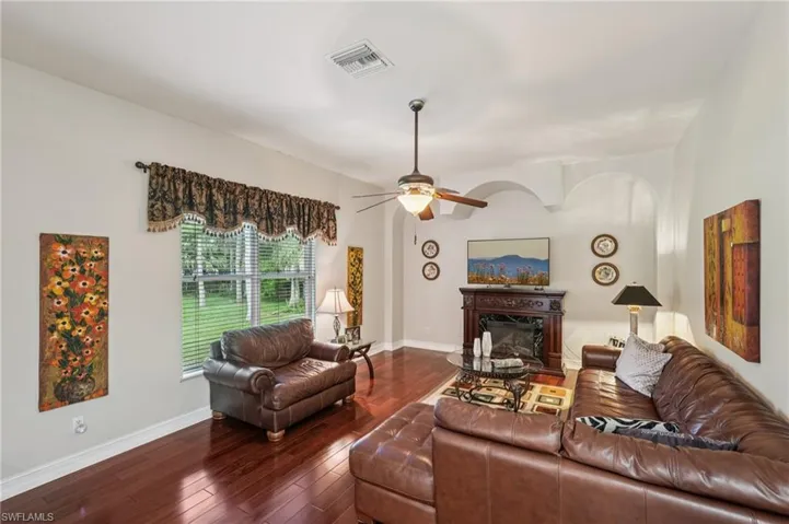 Living area with a glass covered fireplace, hardwood / wood-style flooring, and ceiling fan