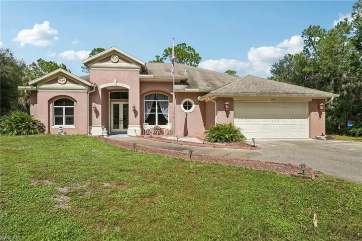 View of front facade with french doors, asphalt driveway, stucco siding, a front lawn, and a garage