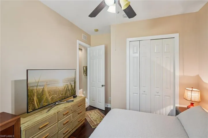 Bedroom with a closet, ceiling fan, and dark wood-type flooring