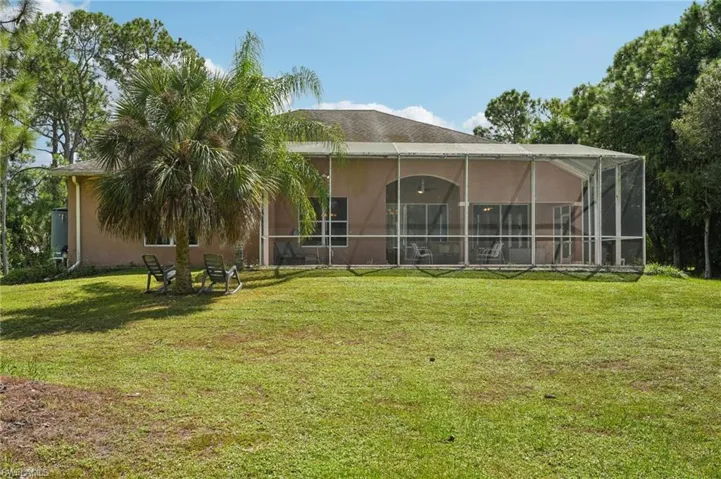 Rear view of property with a lanai, a yard, and a sunroom