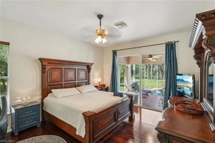 Bedroom with dark wood-style floors, a ceiling fan, and access to exterior