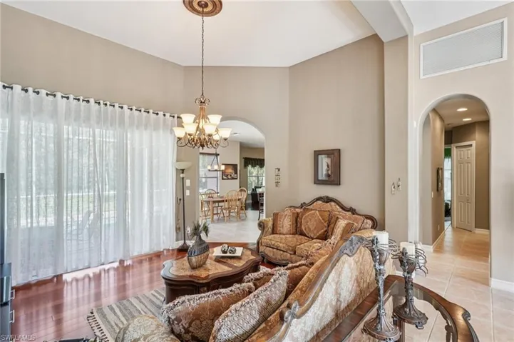 Living area with arched walkways, a towering ceiling, a chandelier, and light tile patterned flooring