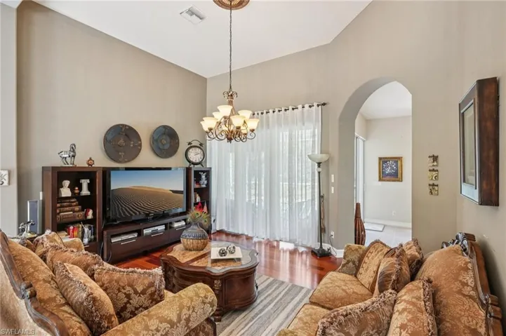 Living area featuring wood finished floors, a chandelier, and arched walkways