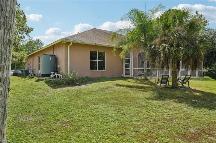Rear view of property featuring a lawn, stucco siding, a sunroom, and roof with shingles