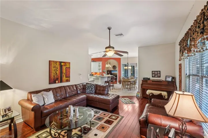 Living area featuring ceiling fan, dark wood-type flooring, plenty of natural light, and a chandelier