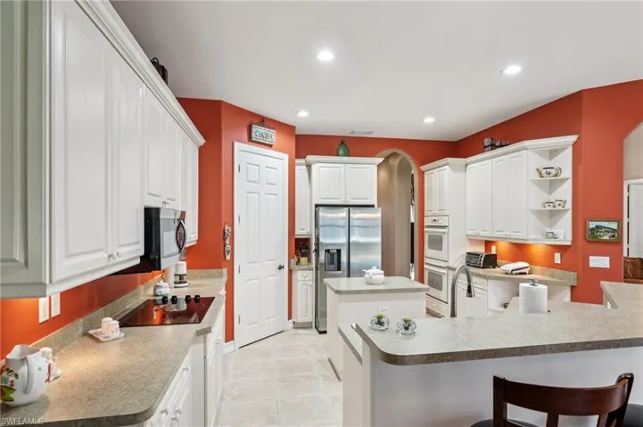 Kitchen featuring white cabinetry, open shelves, arched walkways, a center island, and recessed lighting