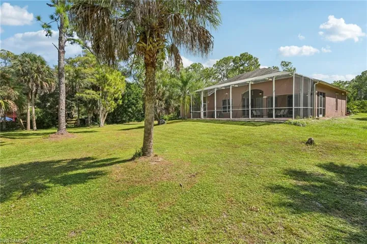 View of grassy yard featuring a sunroom