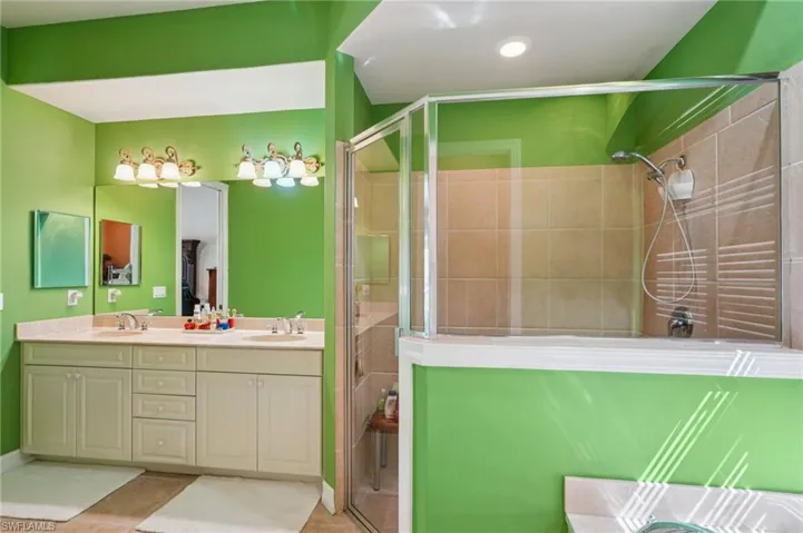 Full bath featuring a shower stall, double vanity, and light tile patterned flooring