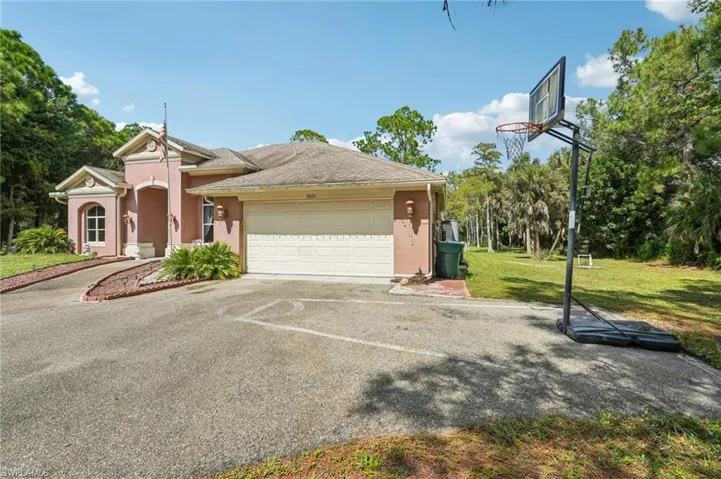 View of front of house featuring stucco siding, driveway, a front lawn, a garage, and a shingled roof