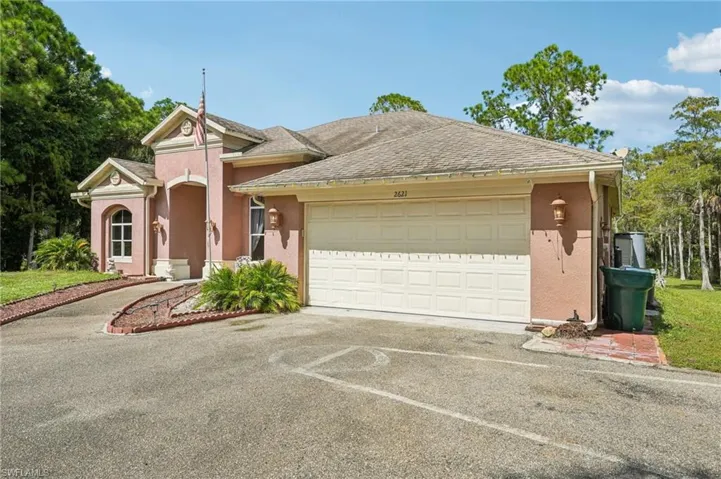 View of front of home with driveway, stucco siding, roof with shingles, and a garage