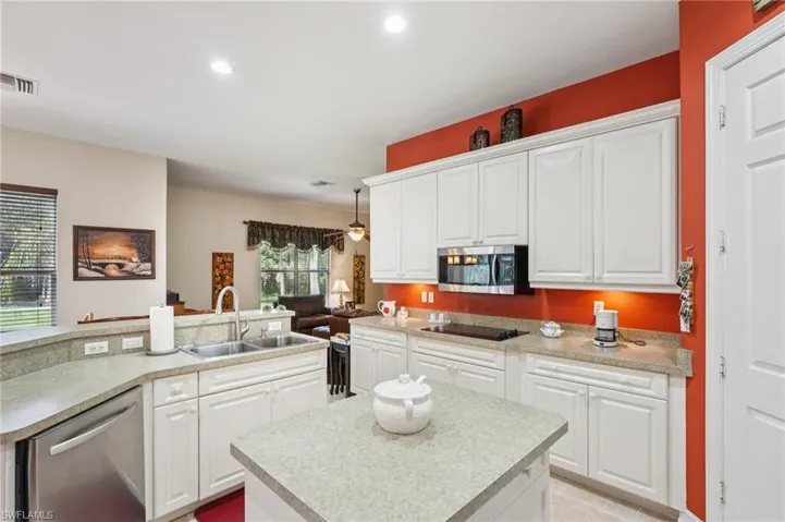 Kitchen with a kitchen island with sink, white cabinets, stainless steel appliances, light countertops, and recessed lighting