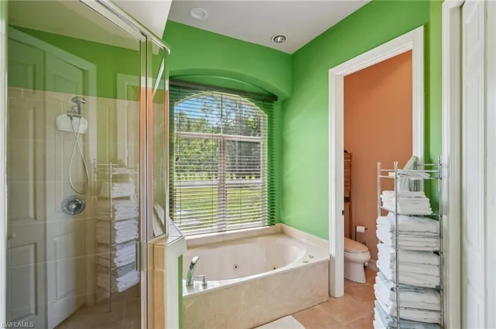 Bathroom with a shower stall, a jetted tub, and tile patterned floors