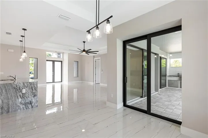 Empty room with a tray ceiling, sink, ceiling fan, and light tile floors