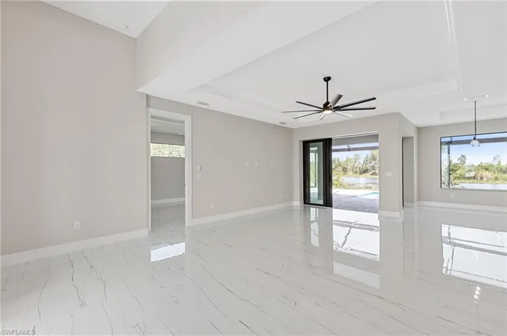 Spare room with a raised ceiling, ceiling fan, and light tile floors