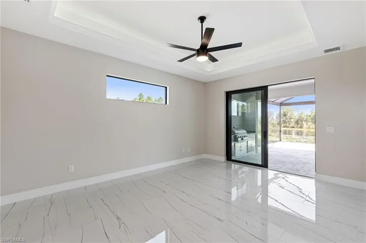 Unfurnished room featuring ceiling fan, light tile flooring, and a tray ceiling