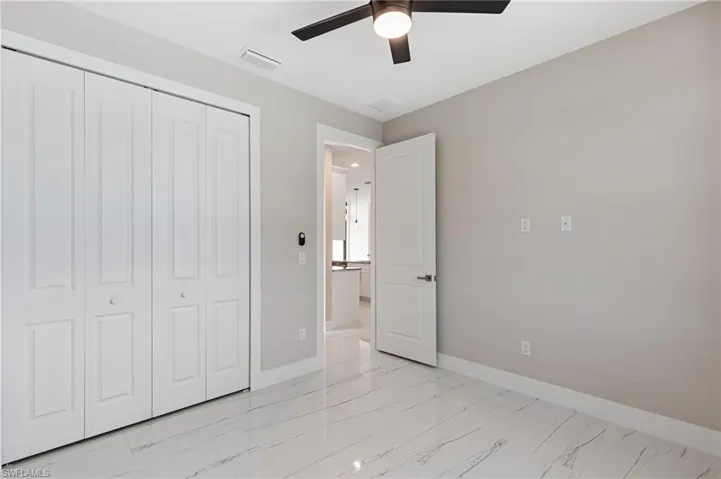 Unfurnished bedroom featuring ceiling fan, a closet, and light tile floors