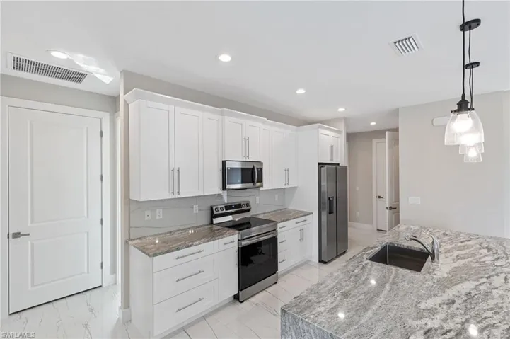 Kitchen featuring stainless steel appliances, tasteful backsplash, white cabinetry, and light tile floors
