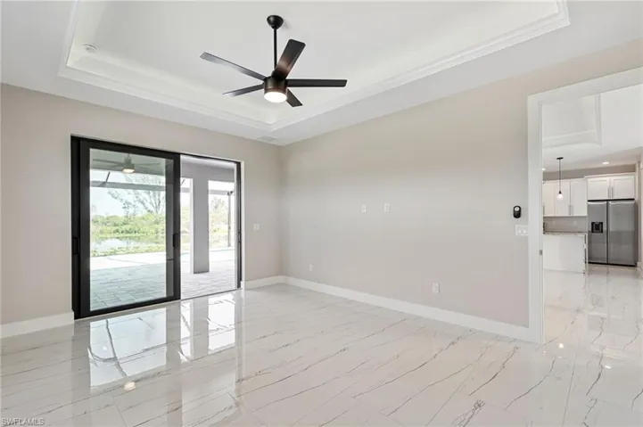 Tiled spare room featuring ceiling fan and a raised ceiling