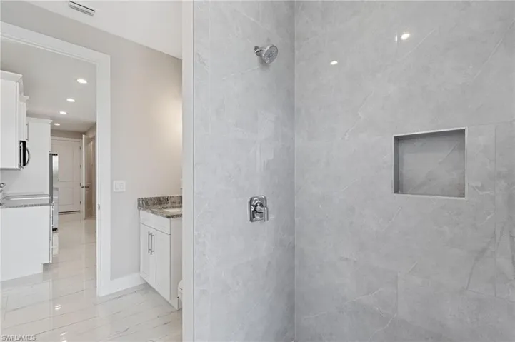 Bathroom with tile floors, a tile shower, and vanity