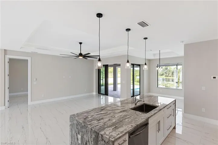 Kitchen with pendant lighting, a raised ceiling, dishwasher, and sink
