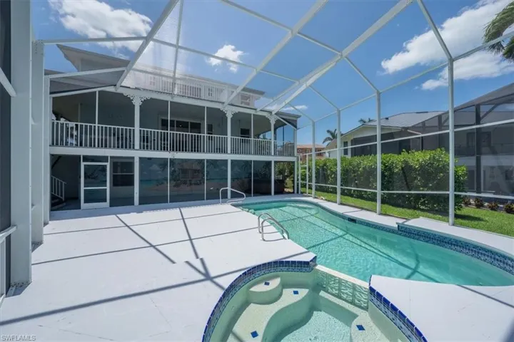 View of pool with screen enclosure, a patio area, and a pool with connected hot tub