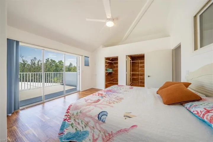 Bedroom with access to exterior, high vaulted ceiling, wood finished floors, and a ceiling fan
