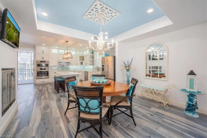 Dining room featuring a tray ceiling, a chandelier, dark wood-type flooring, recessed lighting, and baseboards