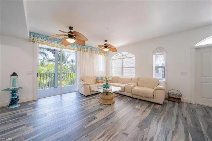 Living area featuring a ceiling fan, wood looking tile floors, and baseboards