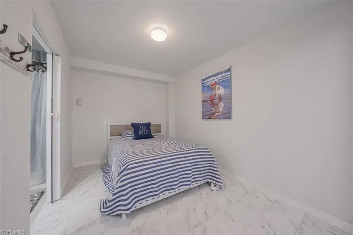Apartment bedroom featuring marble look tile flooring and baseboards