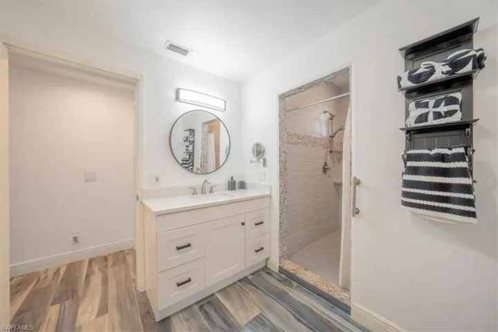 Bathroom featuring a stall shower, vanity, wood finished floors, and baseboards