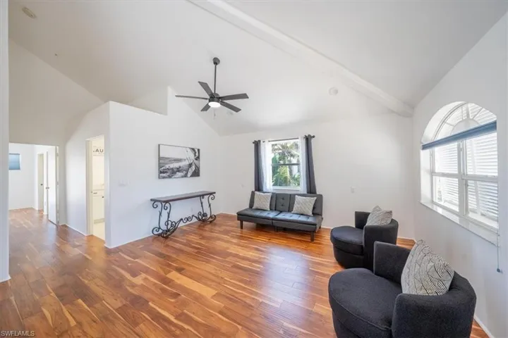 Living room featuring high vaulted ceiling, ceiling fan, and wood finished floors