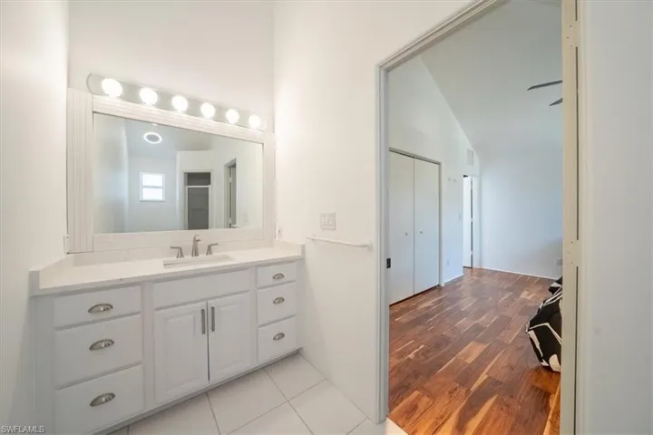 Bathroom featuring vanity, vaulted ceiling, and wood finished floors