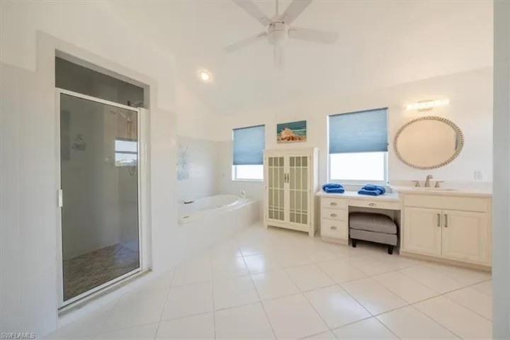 Bathroom featuring lofted ceiling, a shower stall, a garden tub, ceiling fan, and vanity