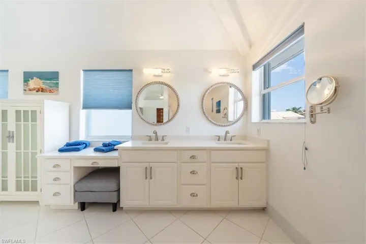 Full bathroom with double vanity, tile patterned flooring, and lofted ceiling