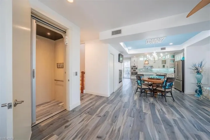 Dining area with a chandelier, wood finished floors, baseboards, a raised ceiling, and recessed lighting