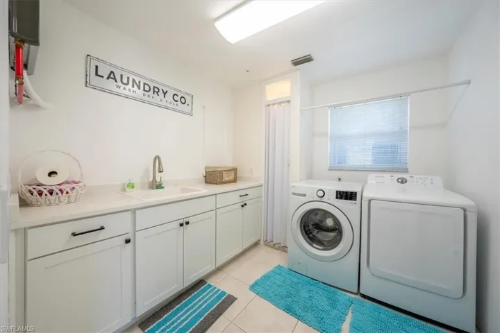 Washroom featuring washer and dryer, cabinet space with folding table and sink.