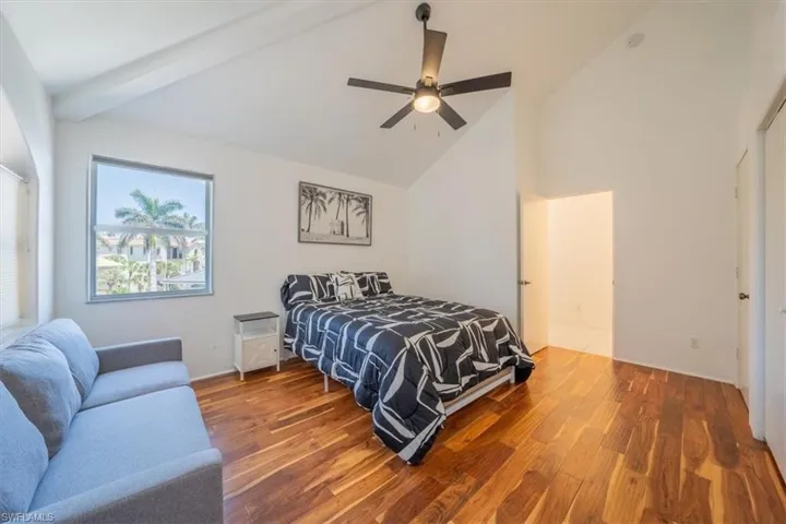 Bedroom with wood finished floors, high vaulted ceiling, ceiling fan, and beam ceiling