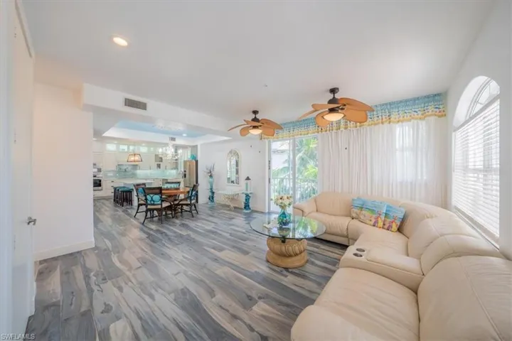 Living room featuring wood looking tile floors, a chandelier, baseboards, ceiling fan, and recessed lighting
