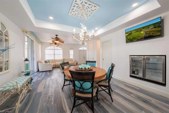 Dining room with wood looking tile floors, a tray ceiling, a chandelier, recessed lighting, and ceiling fan