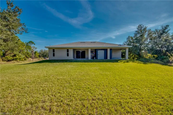 Rear view of property with a lawn and stucco siding