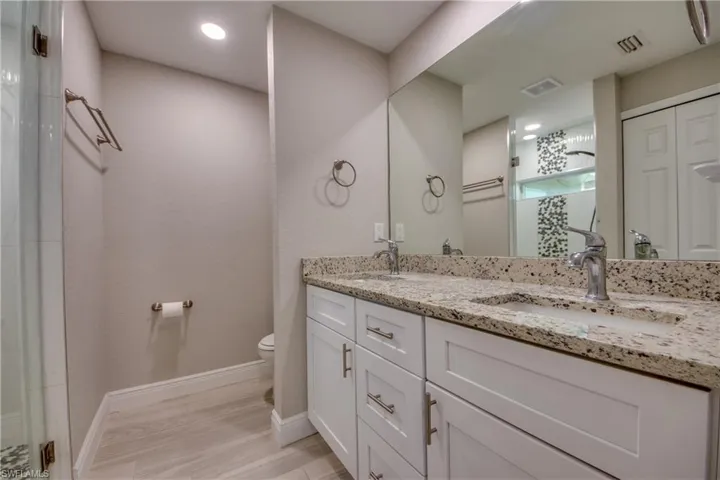 Full bath featuring double vanity, a shower with shower door, recessed lighting, and light wood finished floors