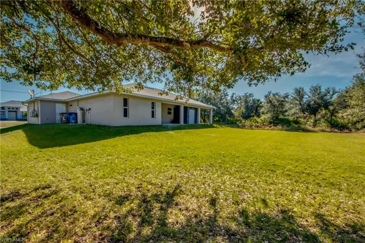 Back of house with a lawn, stucco siding, and a patio area