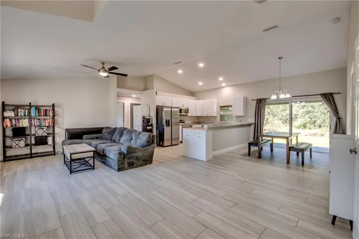 Living area with a chandelier, vaulted ceiling, wood tiled floors, recessed lighting, and ceiling fan