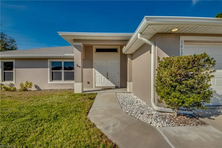 Property entrance featuring stucco siding and a yard