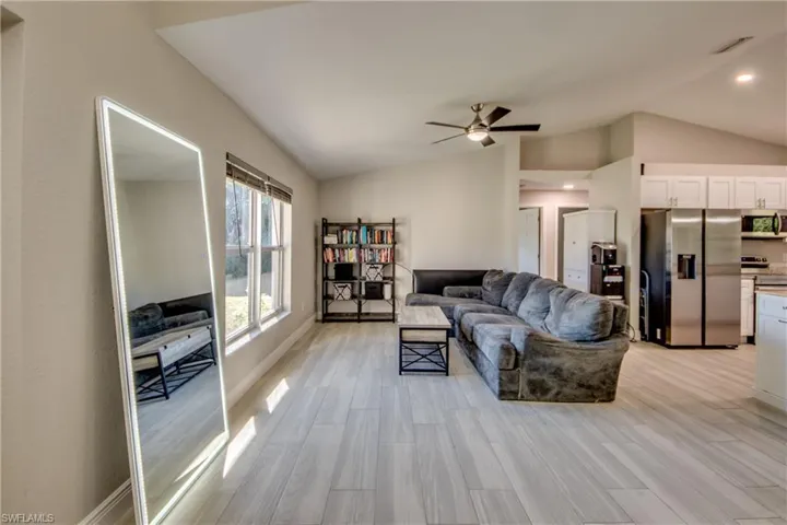 Living room featuring vaulted ceiling, a ceiling fan, and wood tiled floors