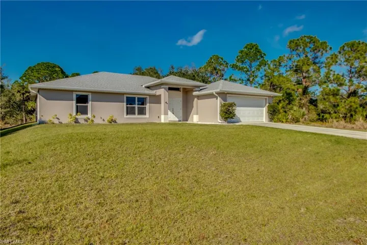 Single story home with stucco siding, a front yard, driveway, and an attached garage
