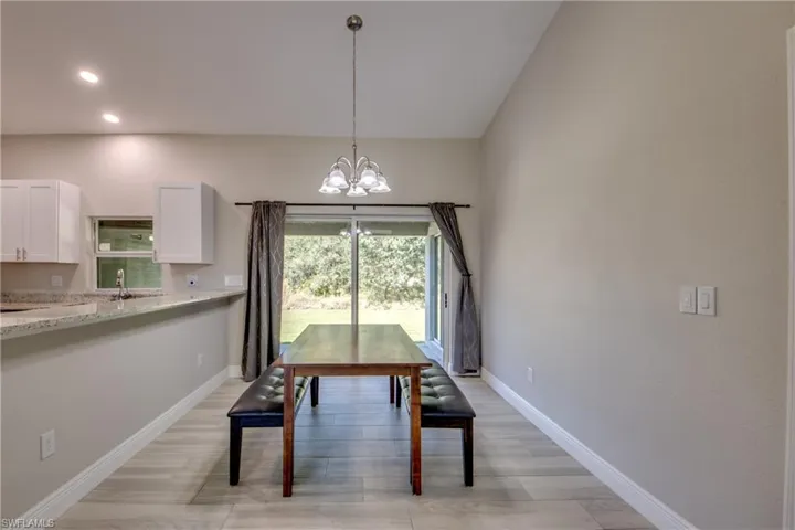 Dining area with a chandelier, vaulted ceiling, and light wood finished floors