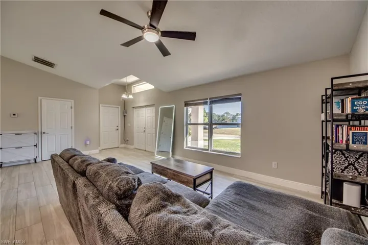 Living area with a ceiling fan, vaulted ceiling, and light wood-type flooring